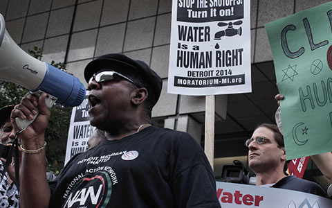 Person speaking through megaphone at rally to stop water shut offs