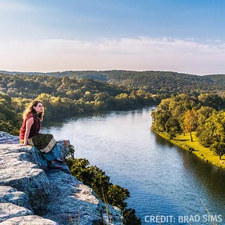 Woman sitting on rocky outcropping overlooking river