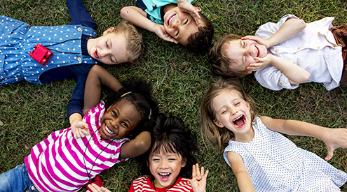 young children lying in a circle on grass