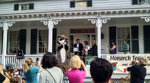 People gathered for Community Wildlife Habitat certification celebration on porch of a white house