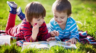 Photo of two kids reading in nature, Shutterstock