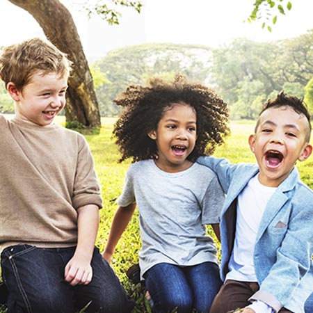 Three children laughing in a field