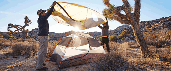 Two people setting up tent at campsite