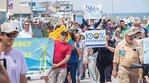 People marching and holding signs at NJ offshore wind renewable energy rally.