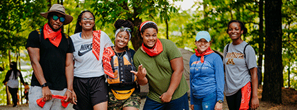 Group of young people standing together and smiling with trees in background