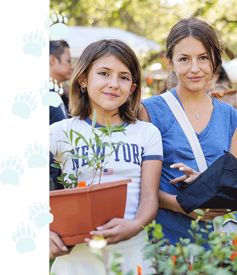 Photo of young people holding plants bordered by pawprint graphic